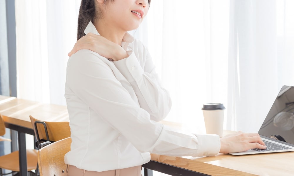 背骨の歪みで肩コリで痛そうな女性